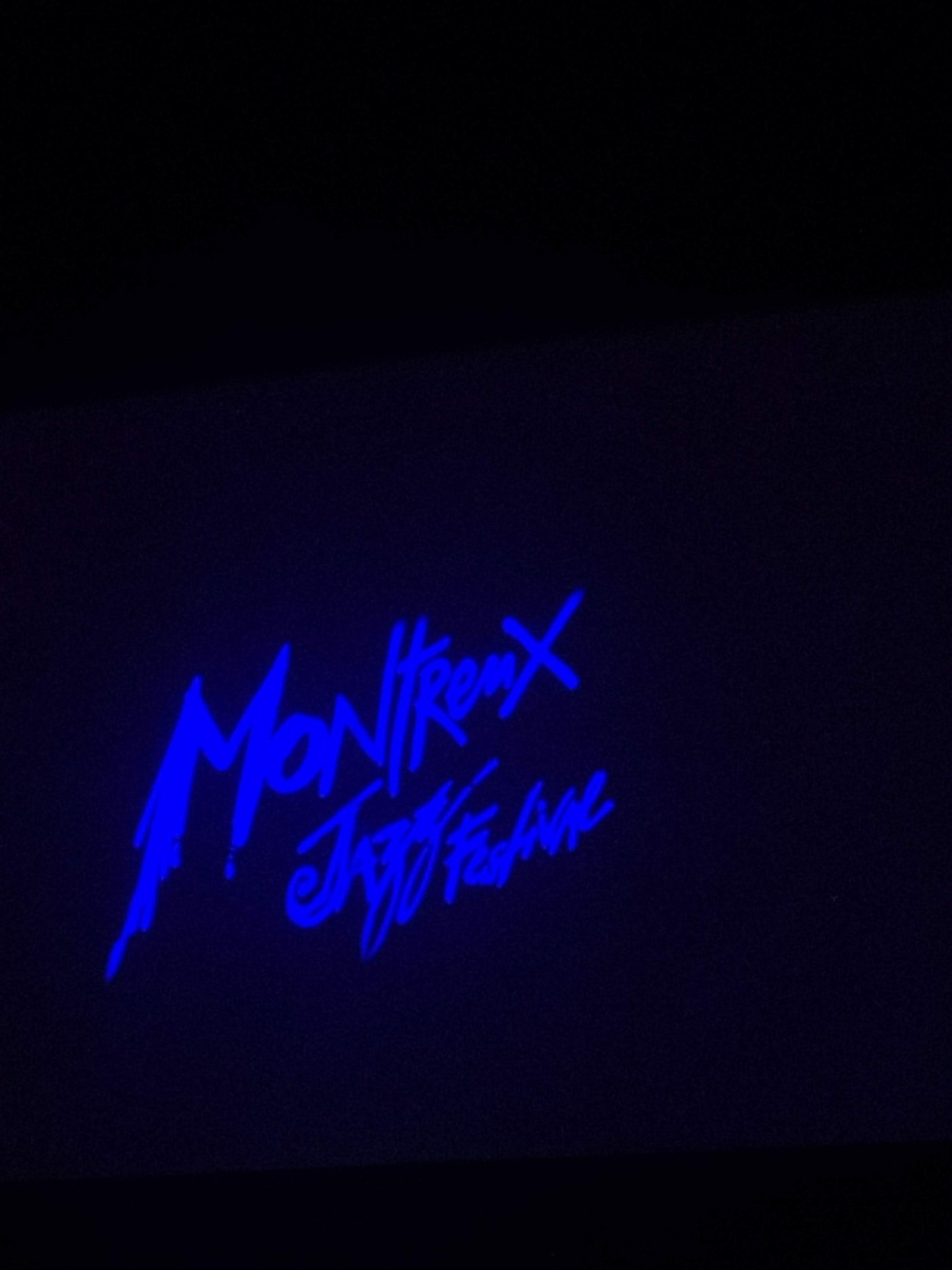 A blue Montreux Jazz Festival projection in a dark room